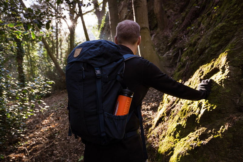Carica immagine in Galleria Viewer, Hiker climbing a steep forest path with an orange LifeSaver Liberty in his backpack
