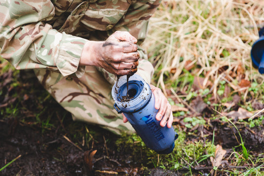 Person in camouflage clothing using a pre filter sponge in a natural setting